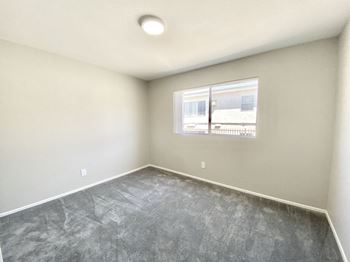 An empty room with a window and concrete floor